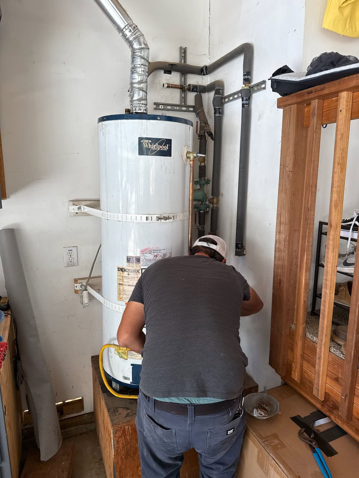 Technician performing maintenance on a silver water heater in El Dorado County, CA for Murray Plumbing